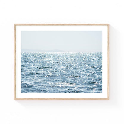 Ocean wall art featuring shimmering sunlight dancing across blue Pacific waters with a soft coastal horizon and airy sky.